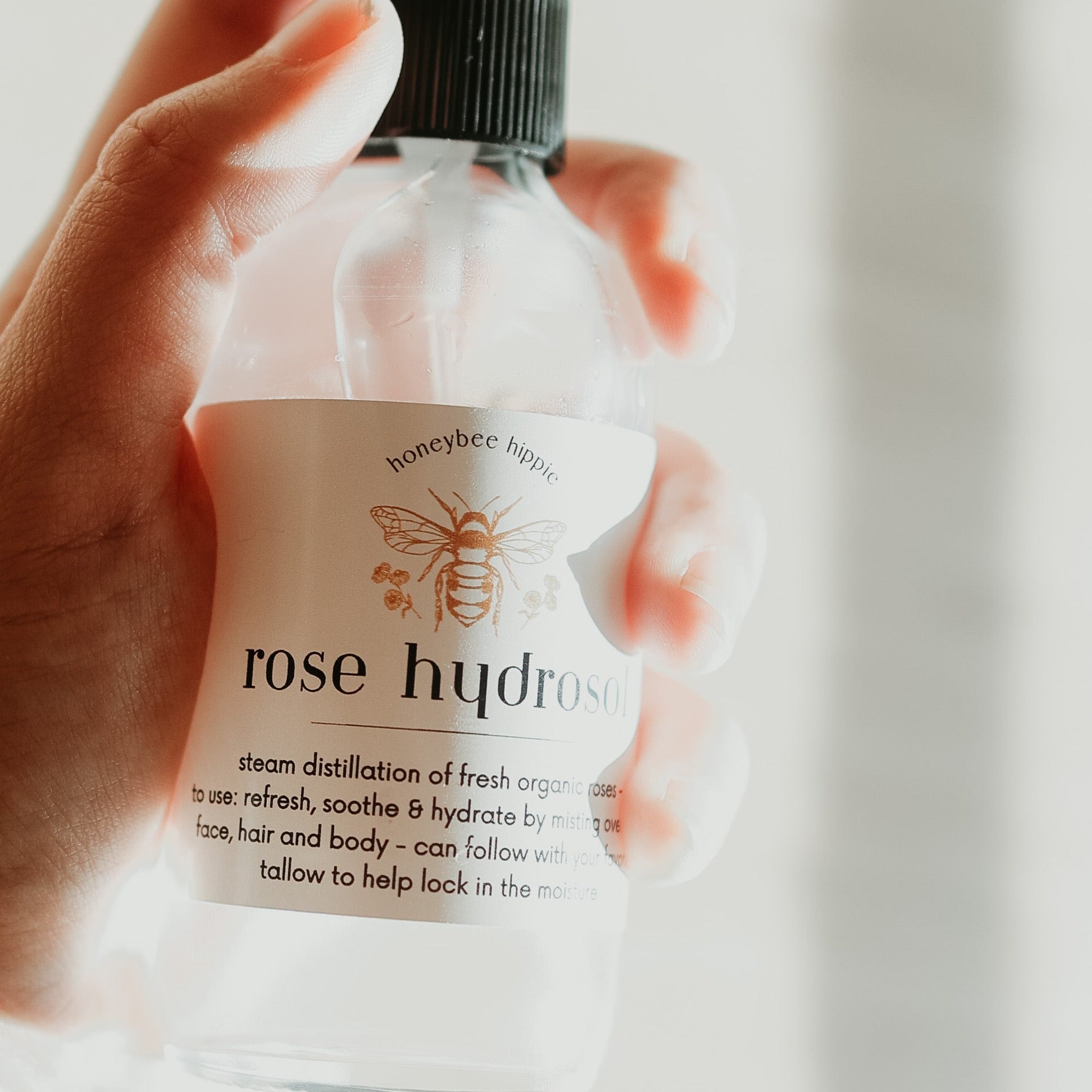 a close up of a bottle of rose hydrosol facial toner spray being held in someone's hand
